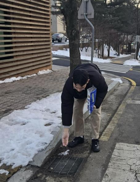 보건소관계자가 모기 유충 방제를 위해 미생물 구제제를 하수구에 투여하고 있는 모습