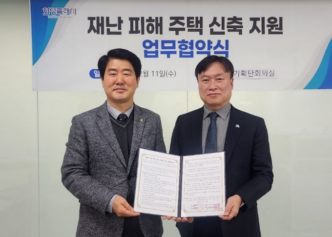 화성특례시 정연송 주택국장과 화성·오산지역건축사회 전영식 회장이 재난 피해 주택 신축 지원 업무협약을 체결하고 협약서를 들고 사진촬영하고 있다.