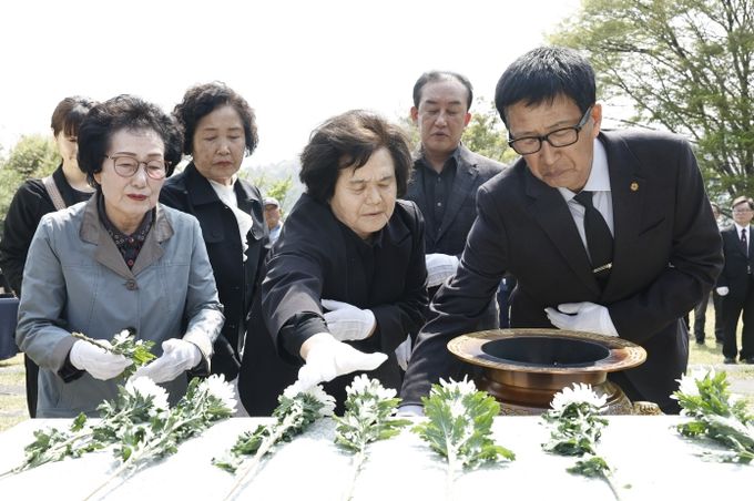 유가족과 참석자들이 제암리 순국 묘역에서 국화를 헌화하며 추모하고 있다